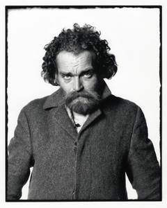 108352 Portret van een bebaarde man met krullend haar en een winterjas aan.